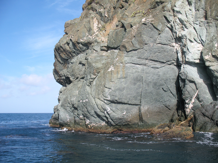 a rock cliff protrudes from the ocean